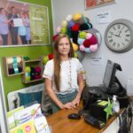 Female standing behind a till looking at the camera