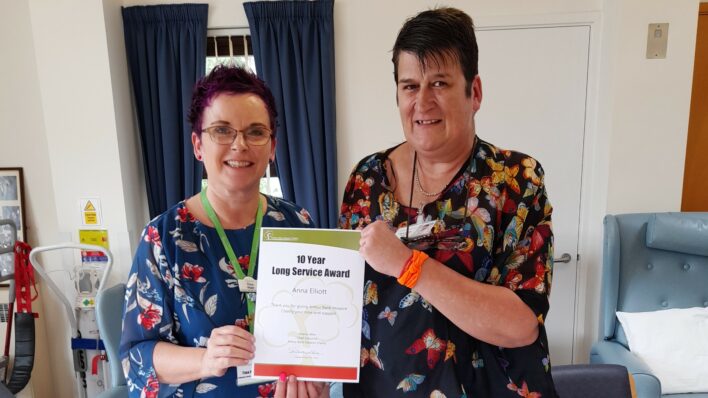 2 females holding a certificate and smiling at the camera