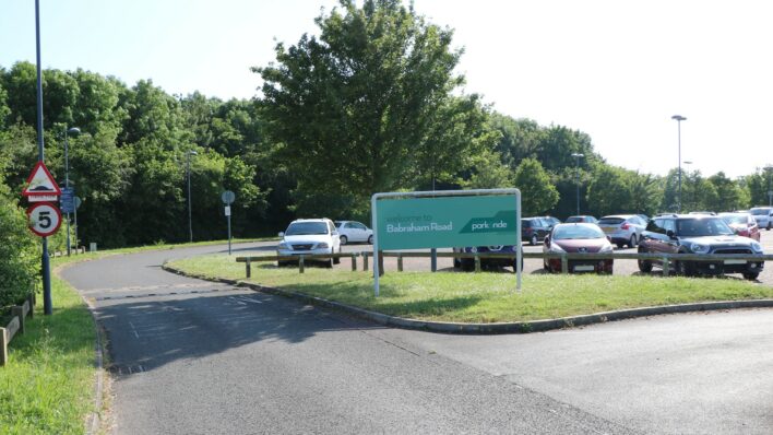 Park and ride green sign and parked cars and a road