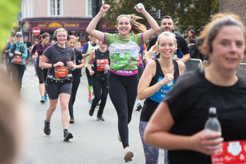 Female arms in the air smiling and running with others