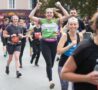 Female arms in the air smiling and running with others