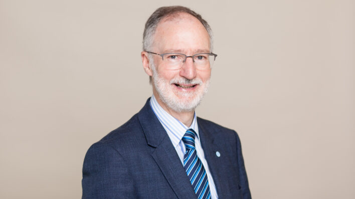 Male wearing glasses and smiling at the camera