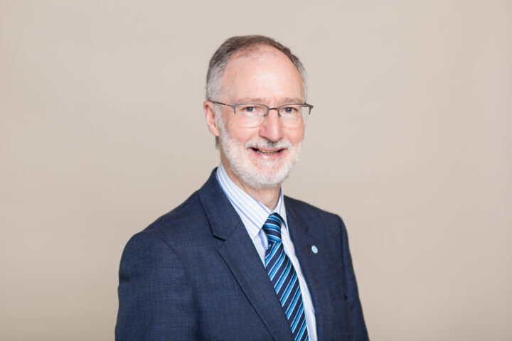 Male wearing glasses and smiling at the camera