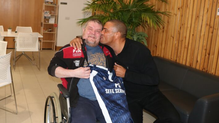 Male in a wheelchair being kissed by a male sitting down