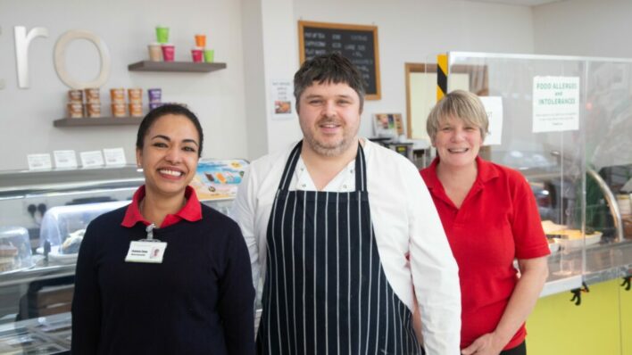 2 females and 1 male chef smiling at the camera in front of Bistro counter