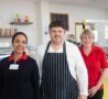 2 females and 1 male chef smiling at the camera in front of Bistro counter