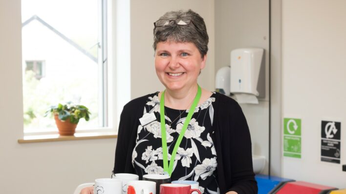 Female smiling at the camera holding a tray of tea cups