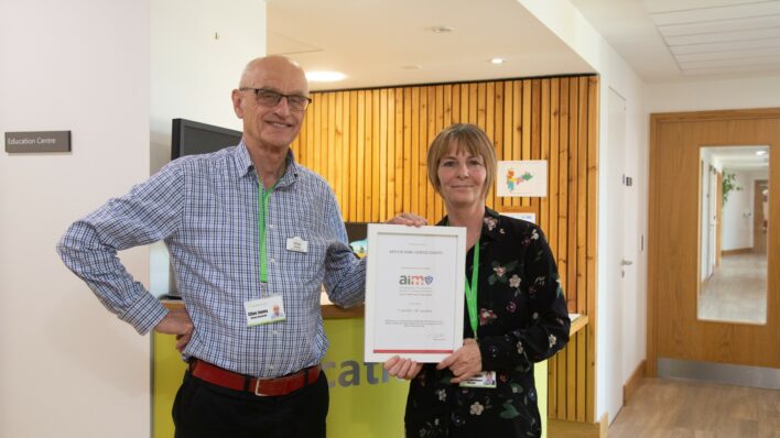 Male and female holding a certificate and looking at the camera