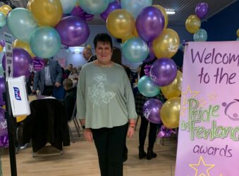 Female standing in front of purple, yellow and blue balloons