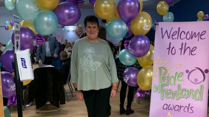 Female standing in front of purple, yellow and blue balloons