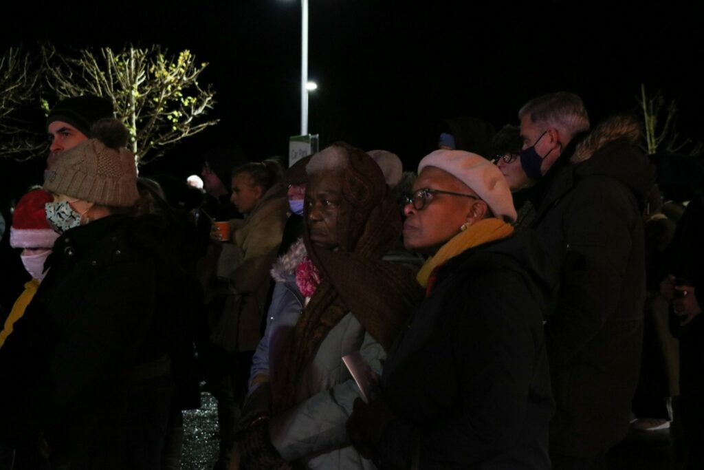 People wearing hats in dark with lit Christmas tree behind