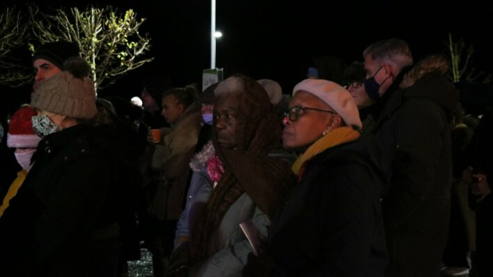 People wearing hats in dark with lit Christmas tree behind