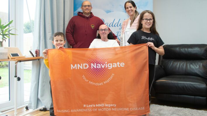 2 males, female and 2 children holding MD Navigate orange banner