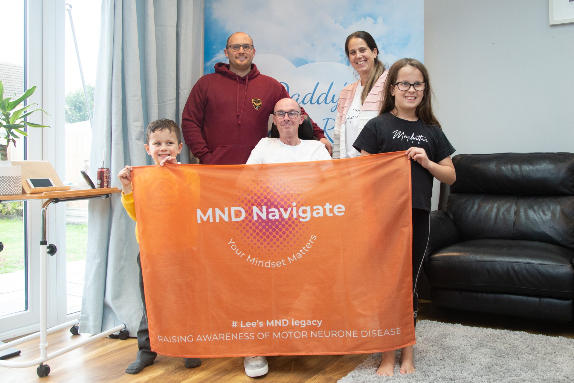 2 males, female and 2 children holding MD Navigate orange banner