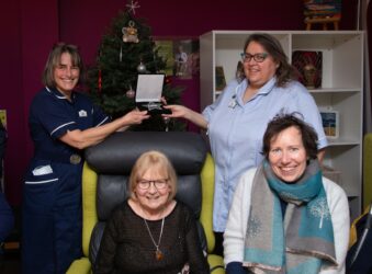 Nurses with presentation box and 2 females sitting in front