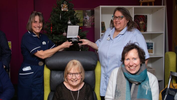 Nurses with presentation box and 2 females sitting in front