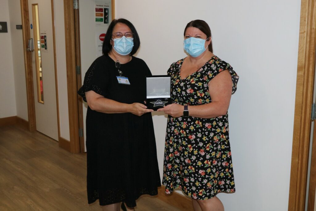 2 females wearing masks holding a presentation box