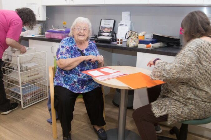 Female smiling at the camera near a table with papers and crafts