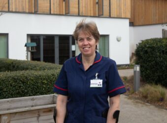 Female nurse in dark blue uniform standing outside the Hospice in the garden