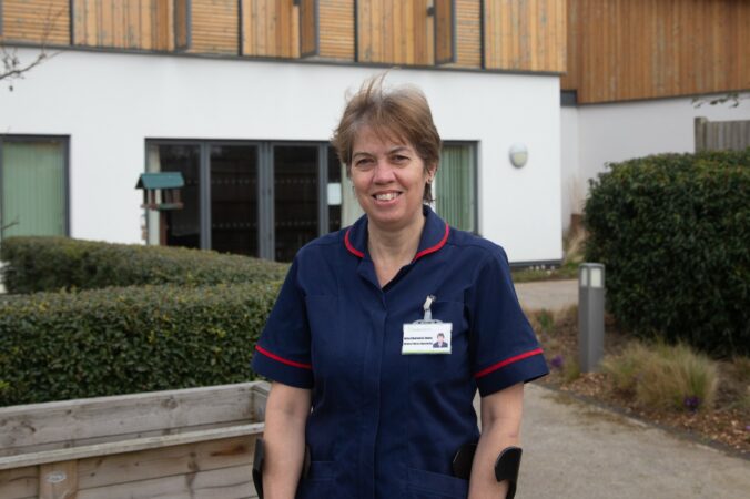 Female nurse in dark blue uniform standing outside the Hospice in the garden