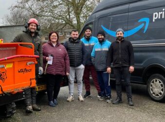 5 males and a female standing next to an Amazon van and smiling at the camera