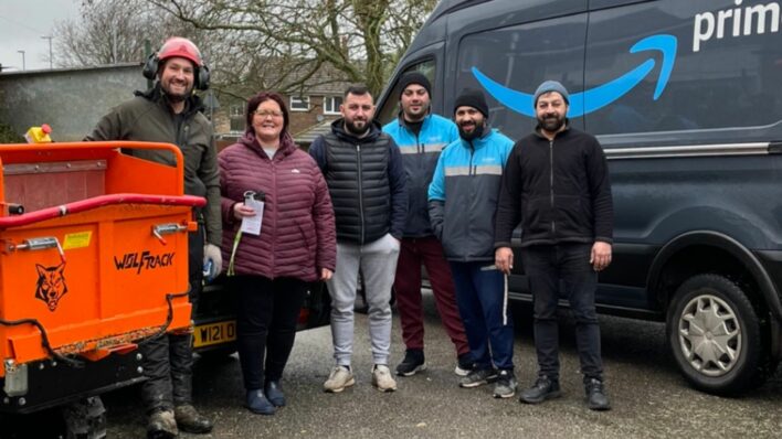 5 males and a female standing next to an Amazon van and smiling at the camera