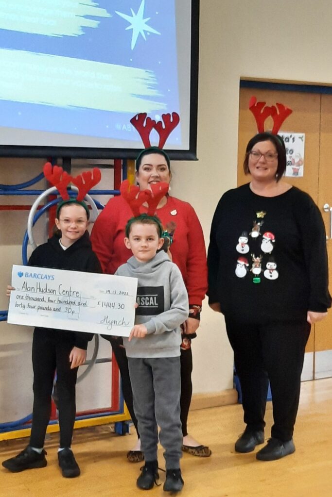 2 females and girl and boy holding a large cheque. All wearing read antlers.