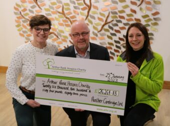 2 females and male holding a large cheque and smiling at the camera