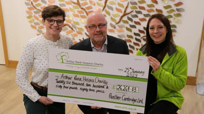 2 females and male holding a large cheque and smiling at the camera