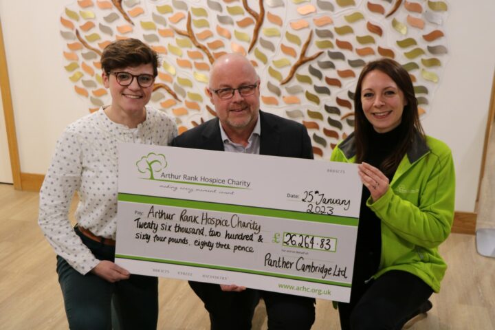 2 females and male holding a large cheque and smiling at the camera
