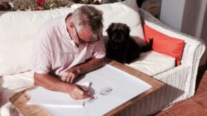Male sitting on a sofa and drawing in an art pad