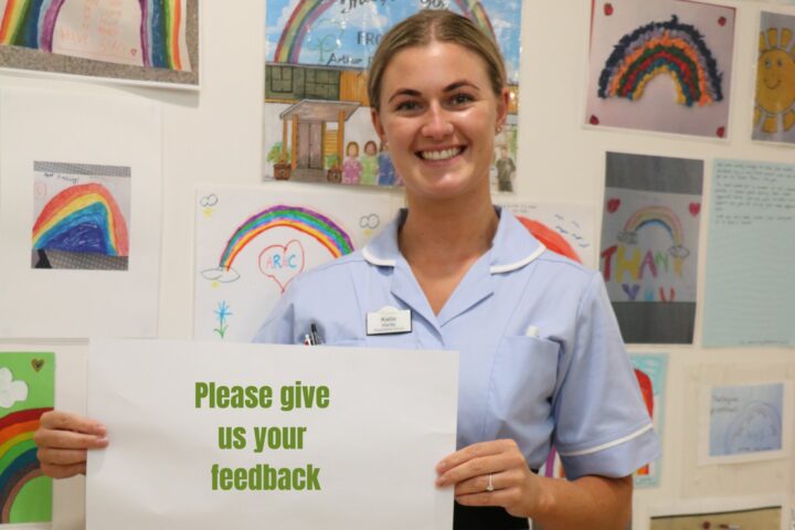 Female nurse holding a sign saying please give us your feedback