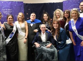 Group of males and females dressed for a Ball one male in a wheelchair