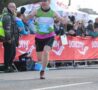 Male running over the finishing line cheering