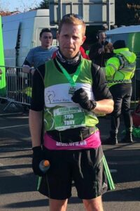 Male holding medal wearing running gear