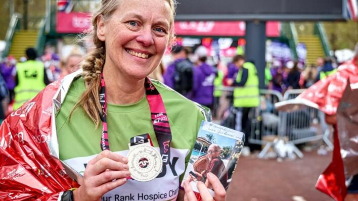 Female London Marathon runner holding their medal and a picture of their late husband