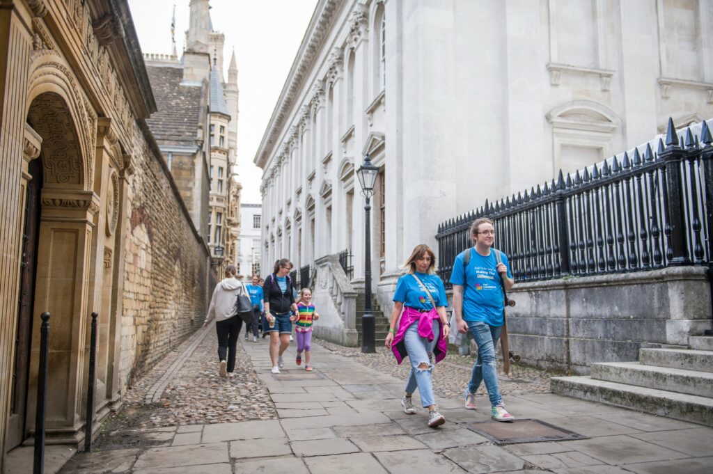 Adults with blue t-shirts walking through Cambridge streets