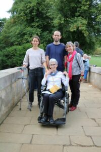 3 females (one in a wheelchair ) and 1 male on a bridge looking at the camera 
