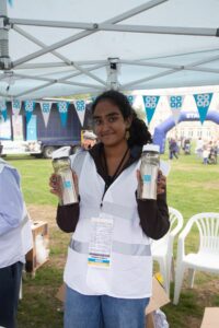 Female wearing white vest holding branded water bottles