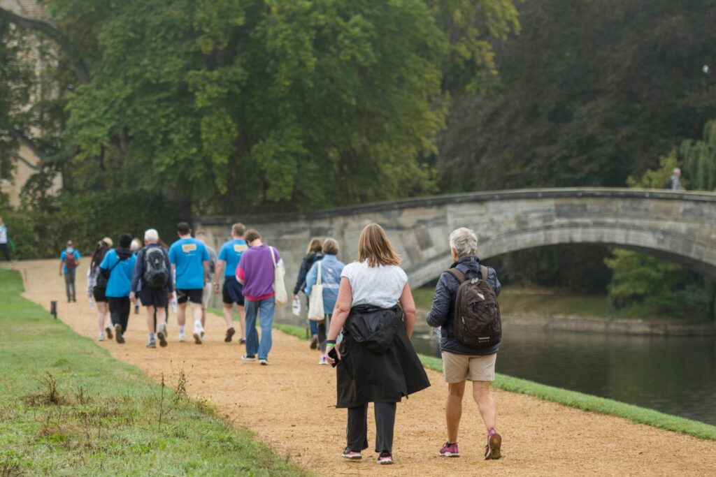 Group of people in a line walking near bridge