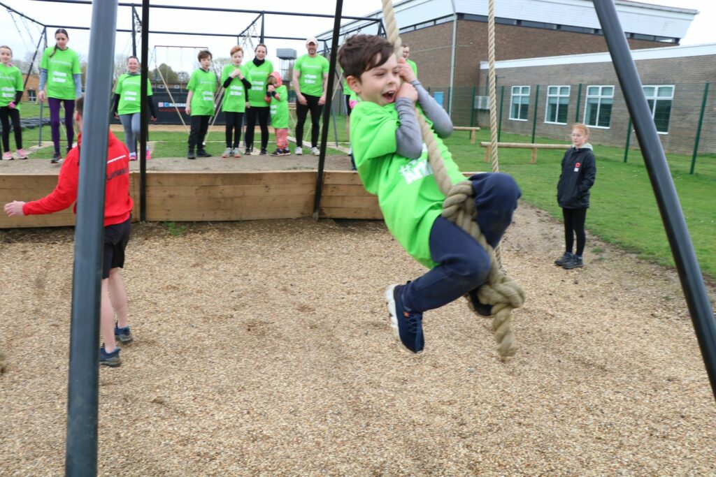 Young male in green tshirt swinging on a rope