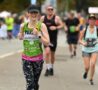 Female wearing green vest running with others