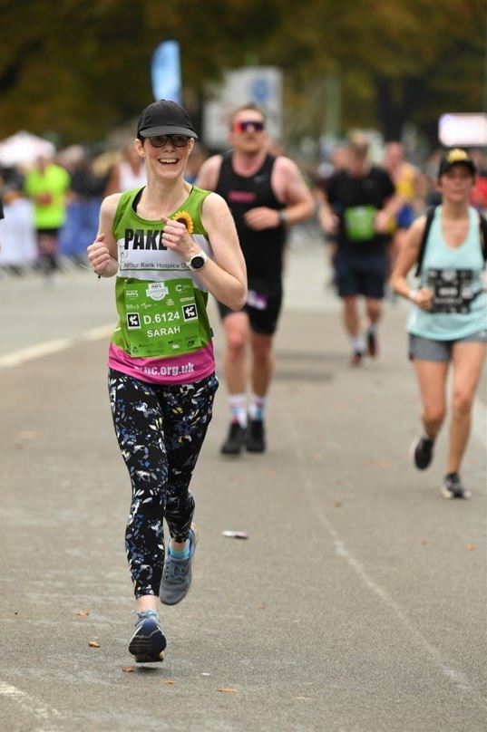 Female wearing green vest running with others 
