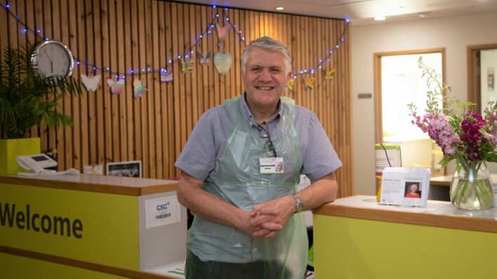 Male leaning on Reception smiling at the camera