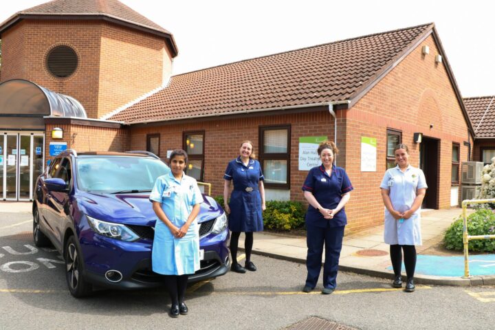 Female nurses standing outside a building and blue car