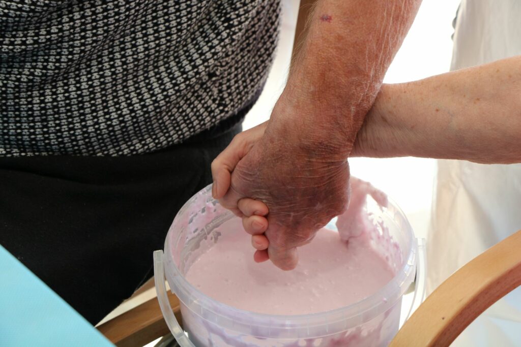 Male and female hand entwinned over a bucket of plaster of paris 