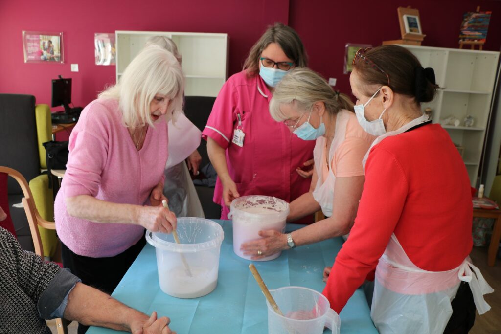 Females standing over a table looking at buckets 