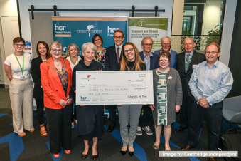 A group of males and females together in a group holding a large cheque