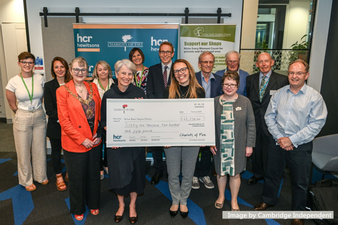 A group of males and females together in a group holding a large cheque