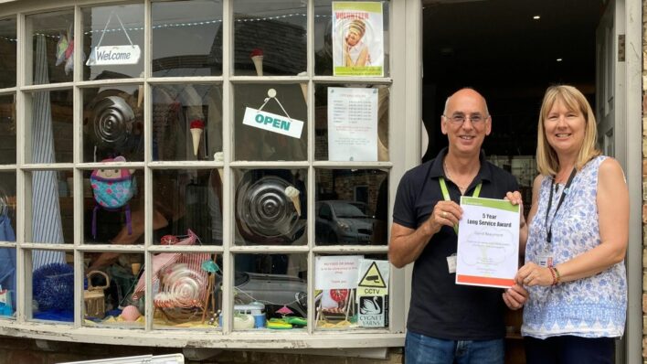 Male and female at the door of a shop holding a 5 year certificate